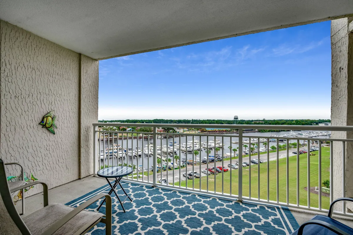 This exterior image features a balcony view adorned with decorative fish on the wall and comfortable outdoor furniture. The setting overlooks tranquil water, suggesting a serene atmosphere perfect for post-golf relaxation or early morning coffee. The space is suitable for small gatherings or unwinding after a day of activities.