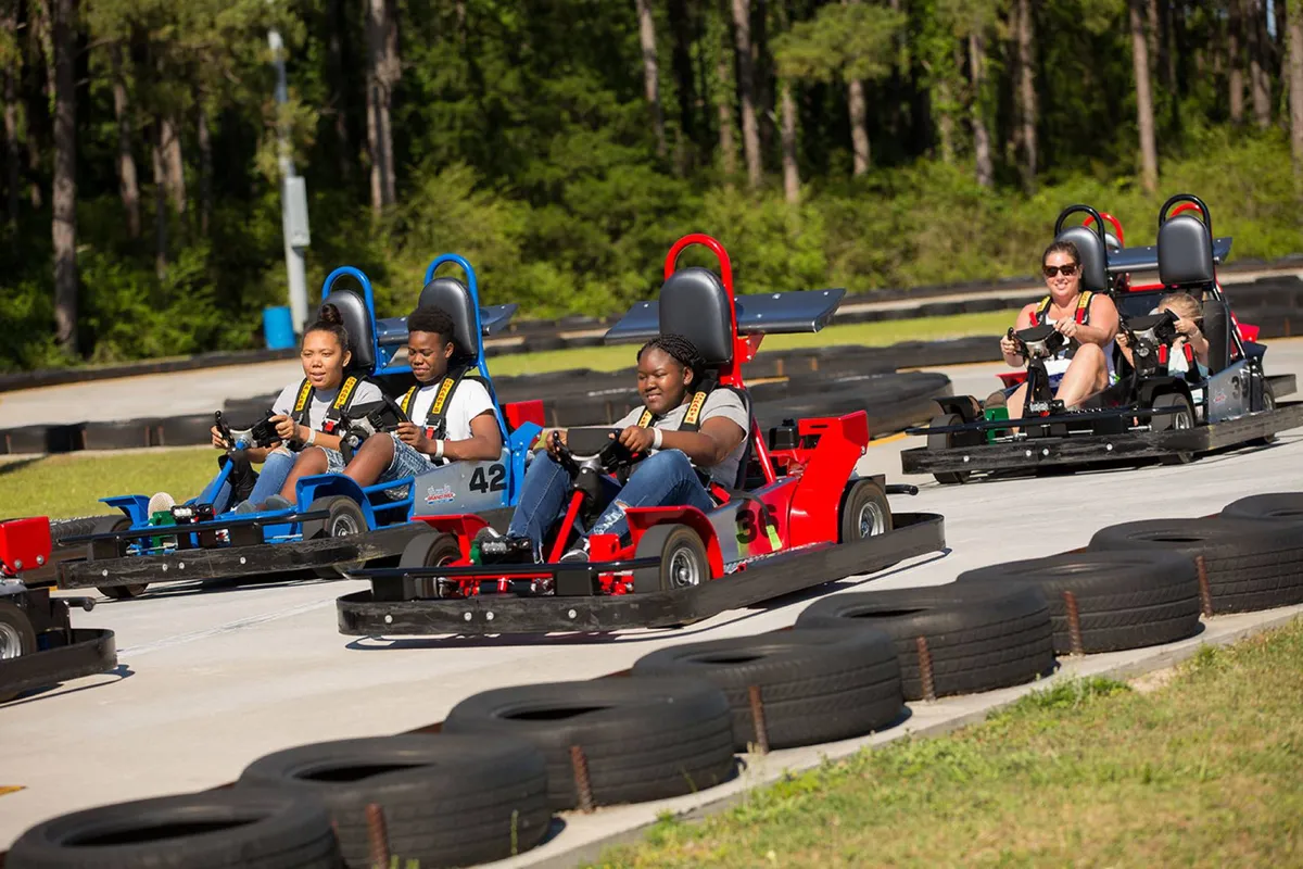 Guests race go-karts around a vibrant racetrack, with excited participants and spectators visible. The energetic setting emphasizes action, group fun, and memorable experiences outside the condo itself.